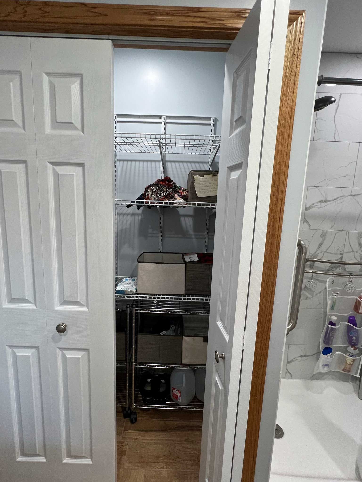 A closet with sliding doors partially open, revealing wire shelving and items inside.
