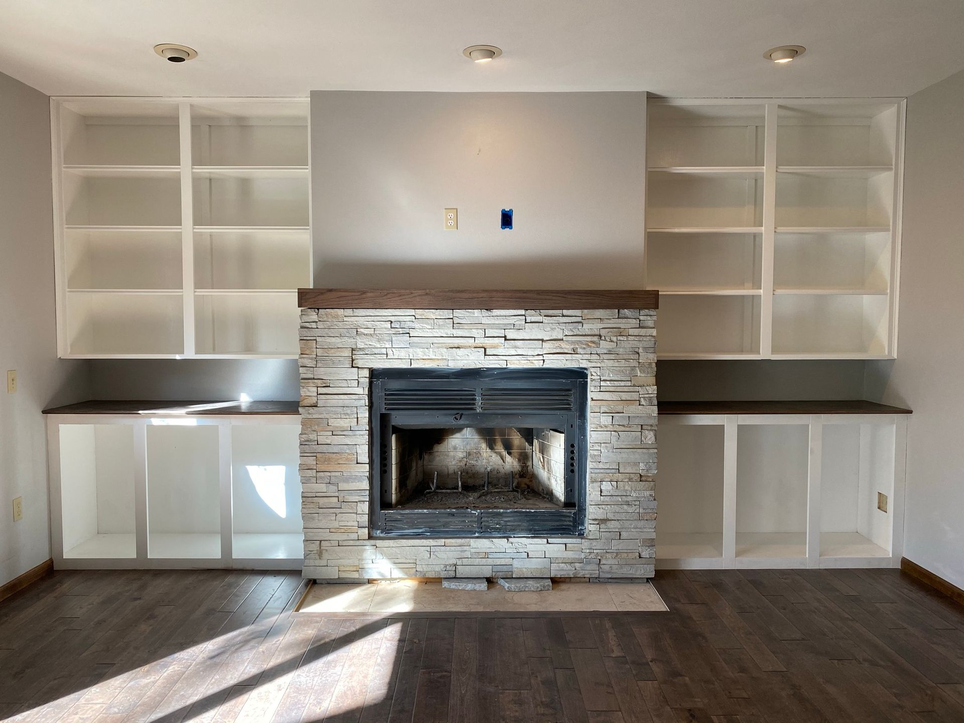 Man installing kitchen cabinets in a room with light green walls and new flooring.