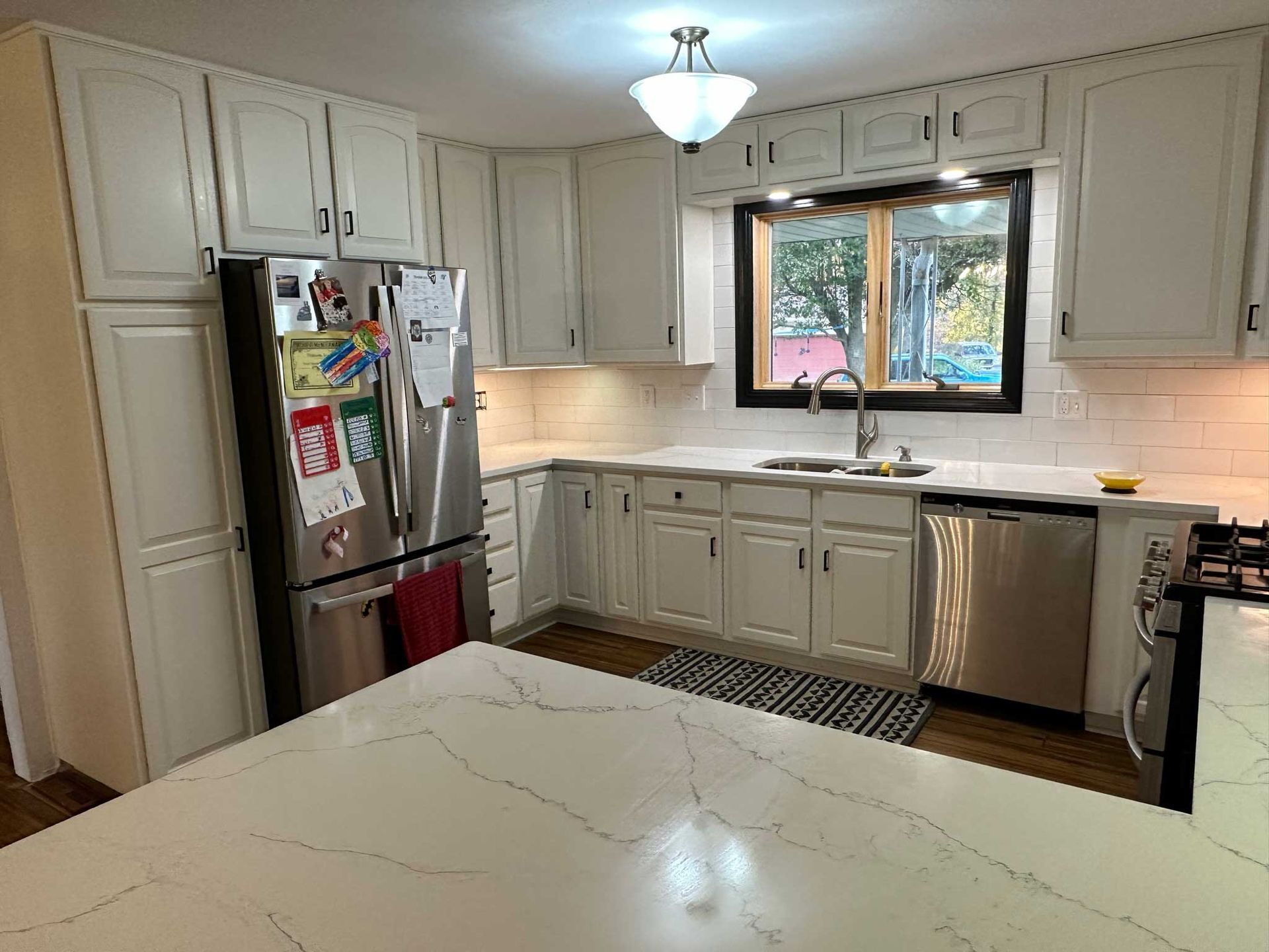 White kitchen with stainless steel appliances, white cabinets, and a quartz countertop island.