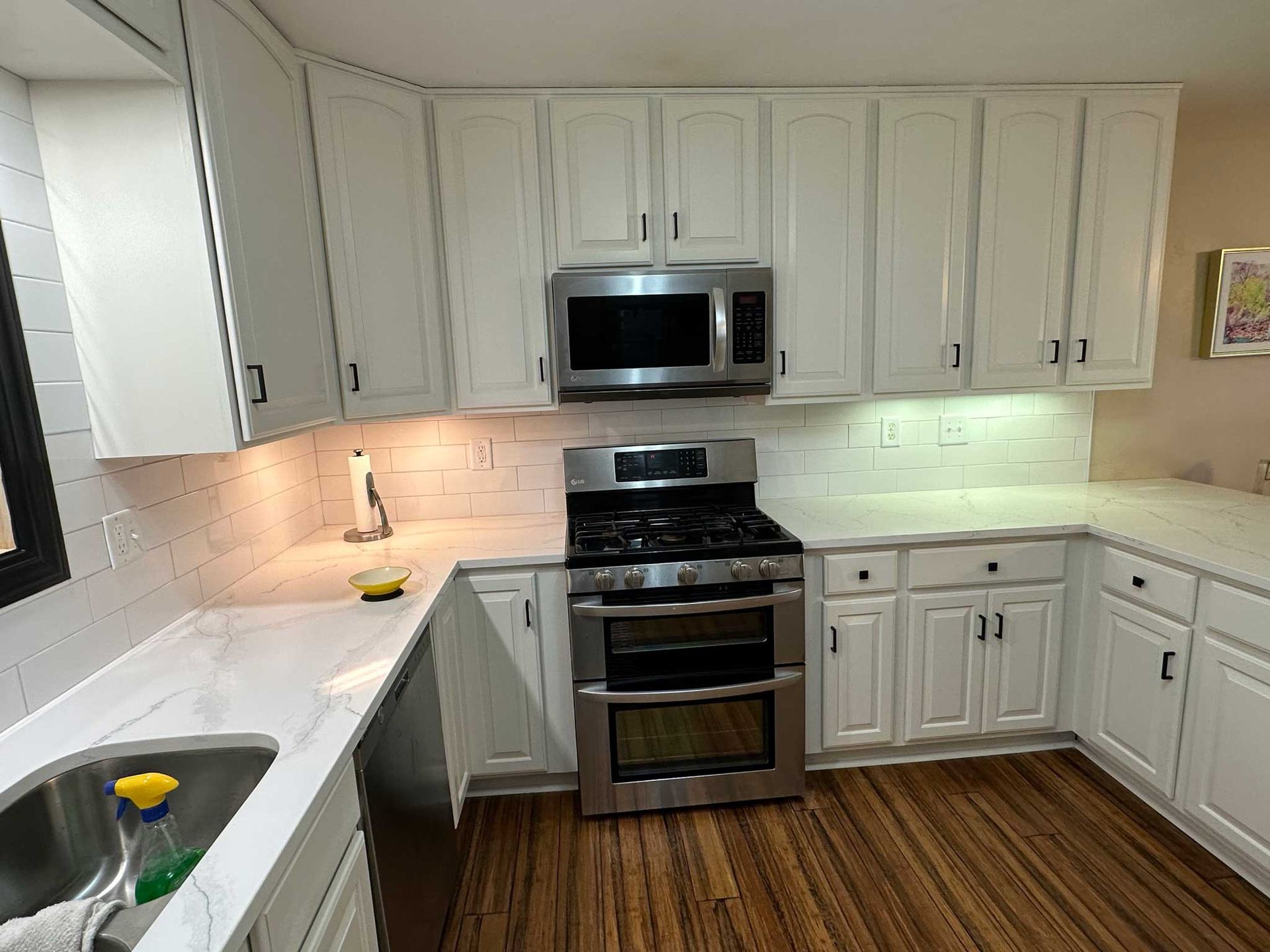 White kitchen with stainless steel appliances, white cabinets, and butcher block floors.