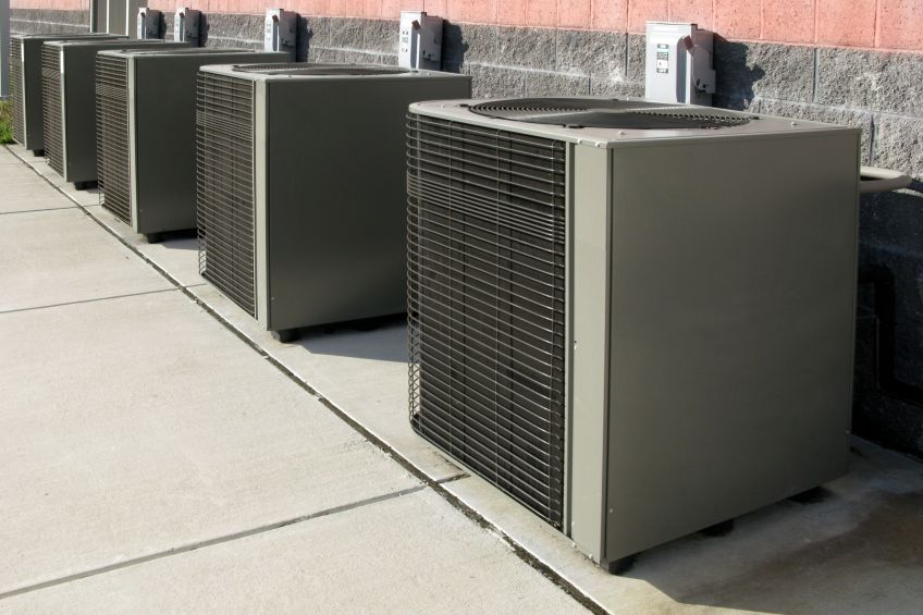 Air conditioning units aligned next to a building wall.