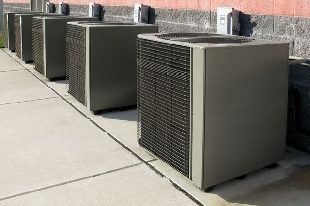 Air conditioning units aligned next to a building wall.