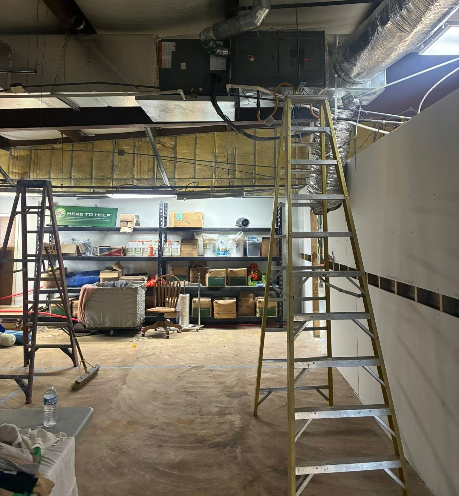 Interior shot of a workshop with two ladders. One ladder is next to a wall, the other is further away.