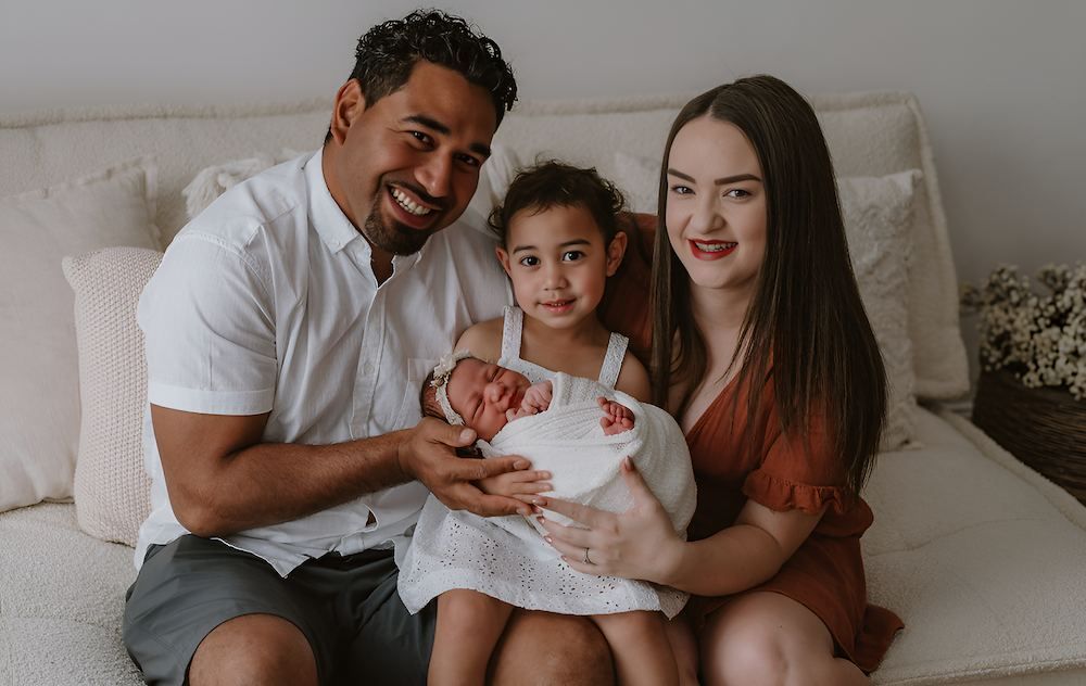 A Family is Sitting on a Couch Holding a Newborn Baby — Median Law In Bundaberg Central, QLD