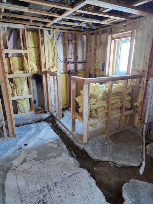 Partially renovated room with exposed framing, insulation, and unfinished floor walls