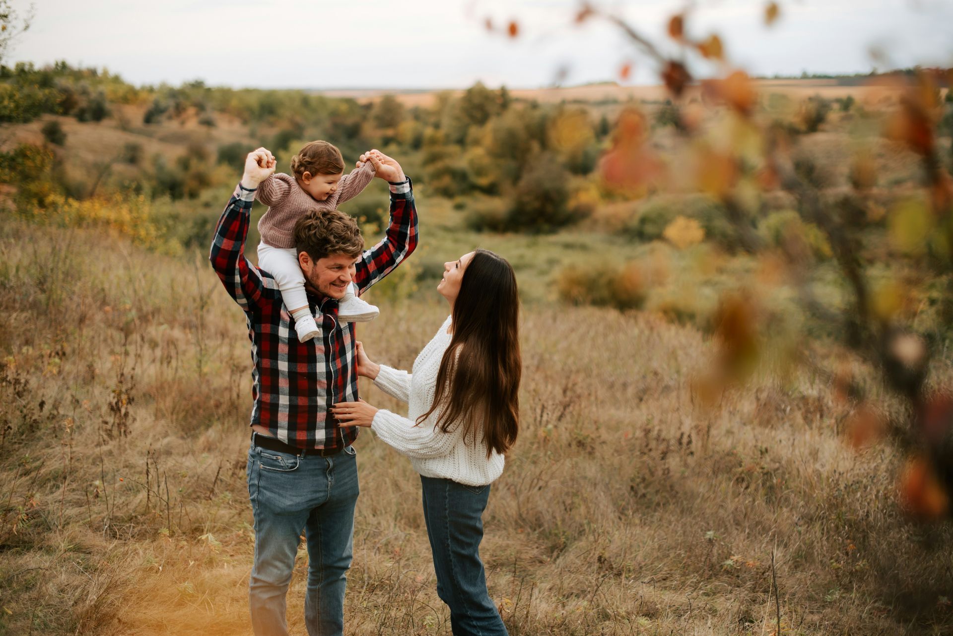 A family is walking through a field holding hands.