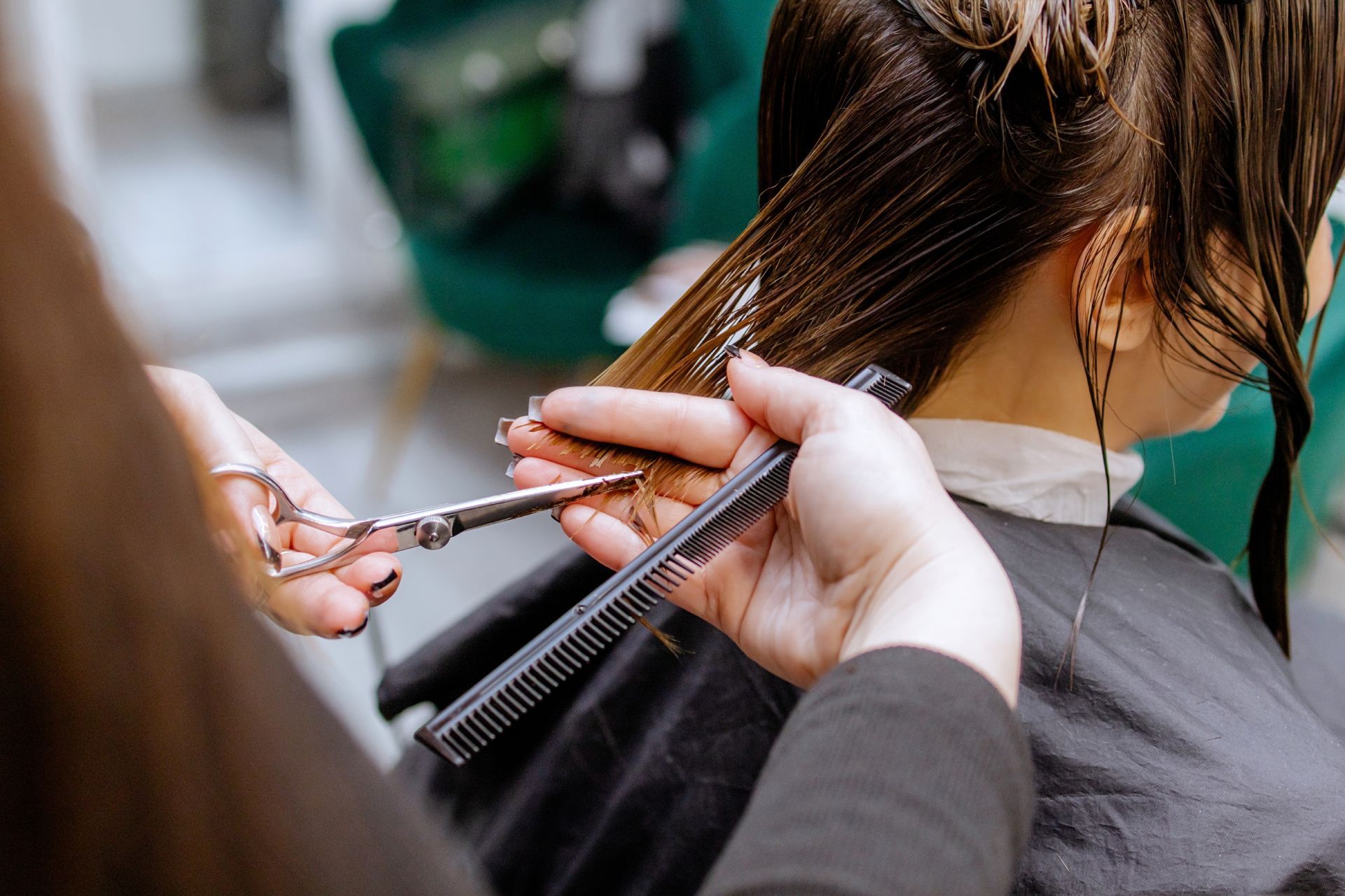 Hairdresser cutting hair with scissors and comb in a salon.