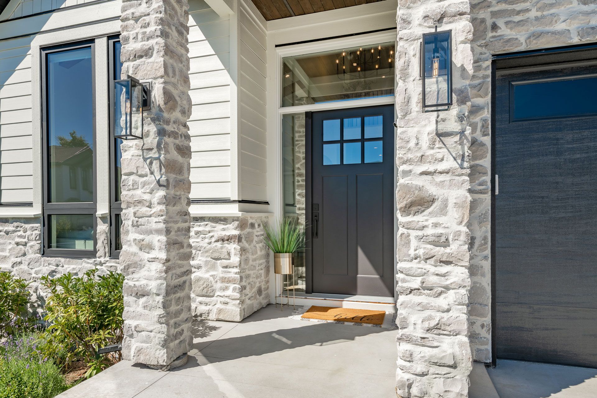 Exterior of modern home with stone facade, dark front door, and garage door.