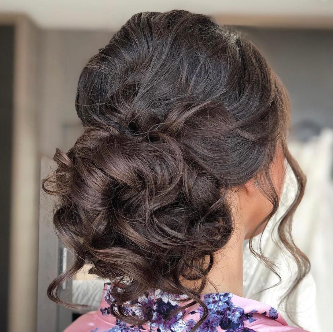 woman with loose curls in a low bun