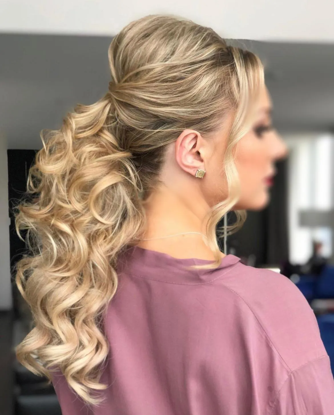 The woman is wearing a pink shirt and has her hair in a ponytail.