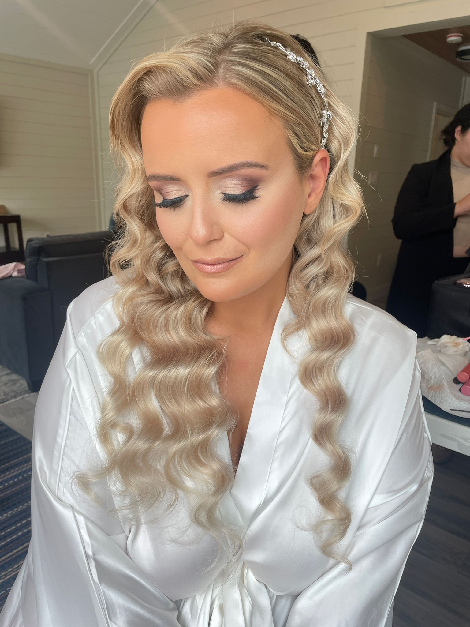 A woman in a white robe is getting ready for her wedding.