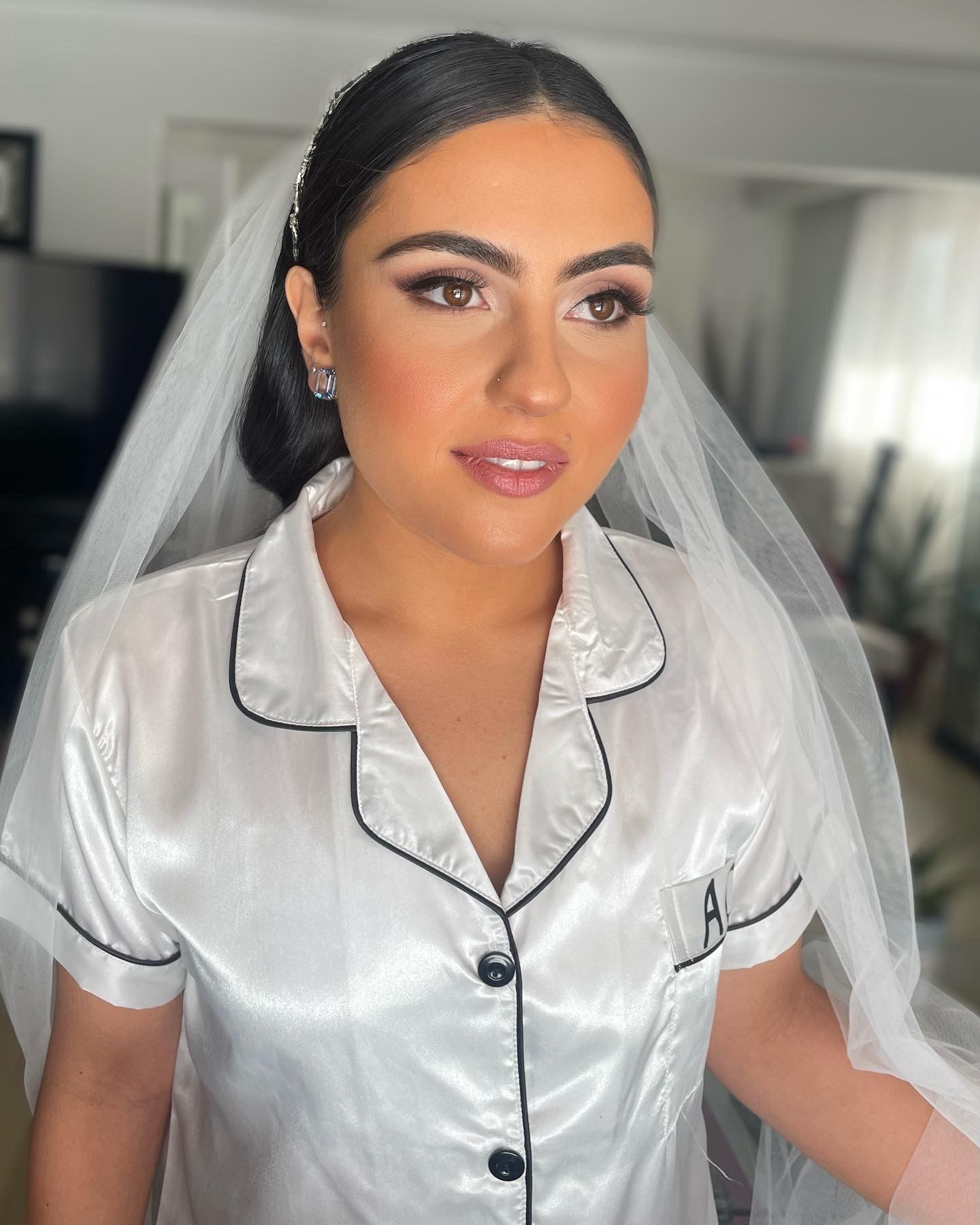 A woman in a white shirt and veil is standing in a room.
