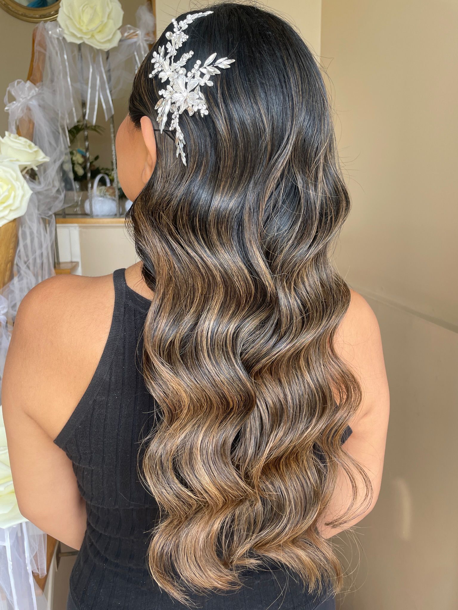 A woman with long wavy hair is wearing a headpiece.