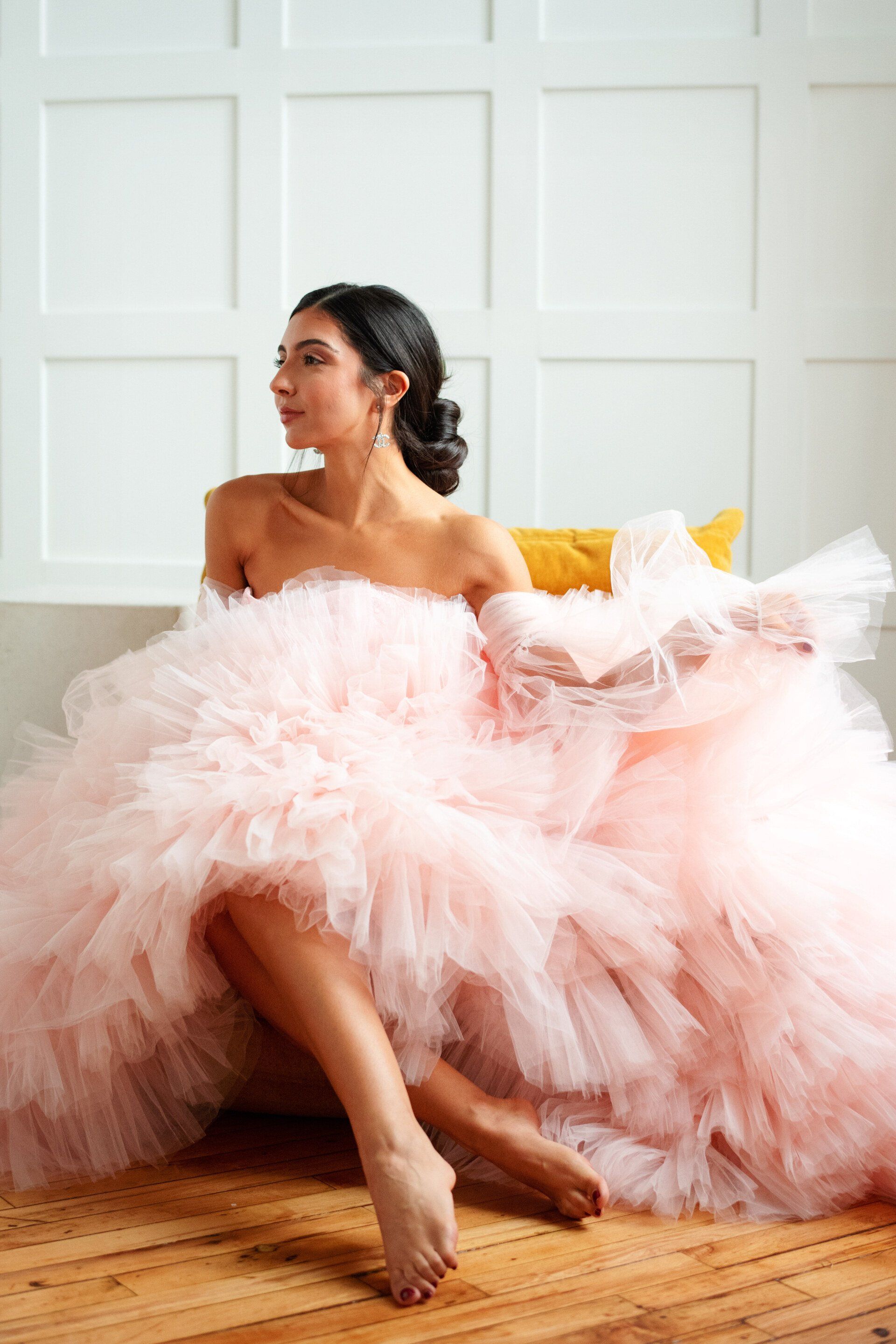 A woman in a pink tulle dress is sitting on a couch.