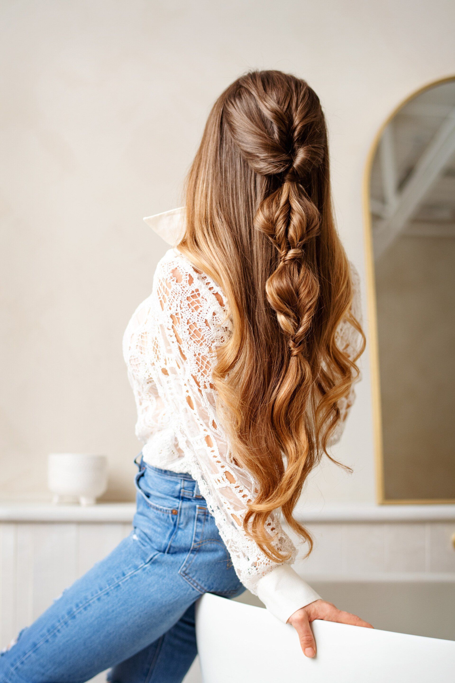 A woman with long hair is sitting on a chair with her back to the camera.