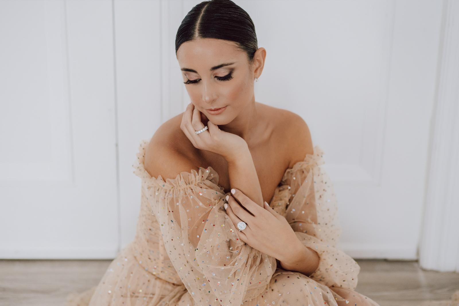 A woman in a dress is sitting on the floor with her hands on her face.
