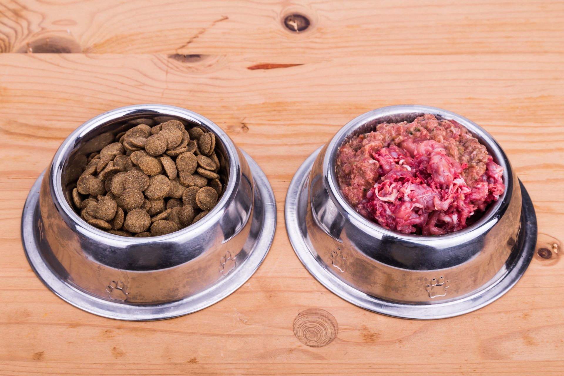 Two bowls of dog food are sitting on a wooden table.