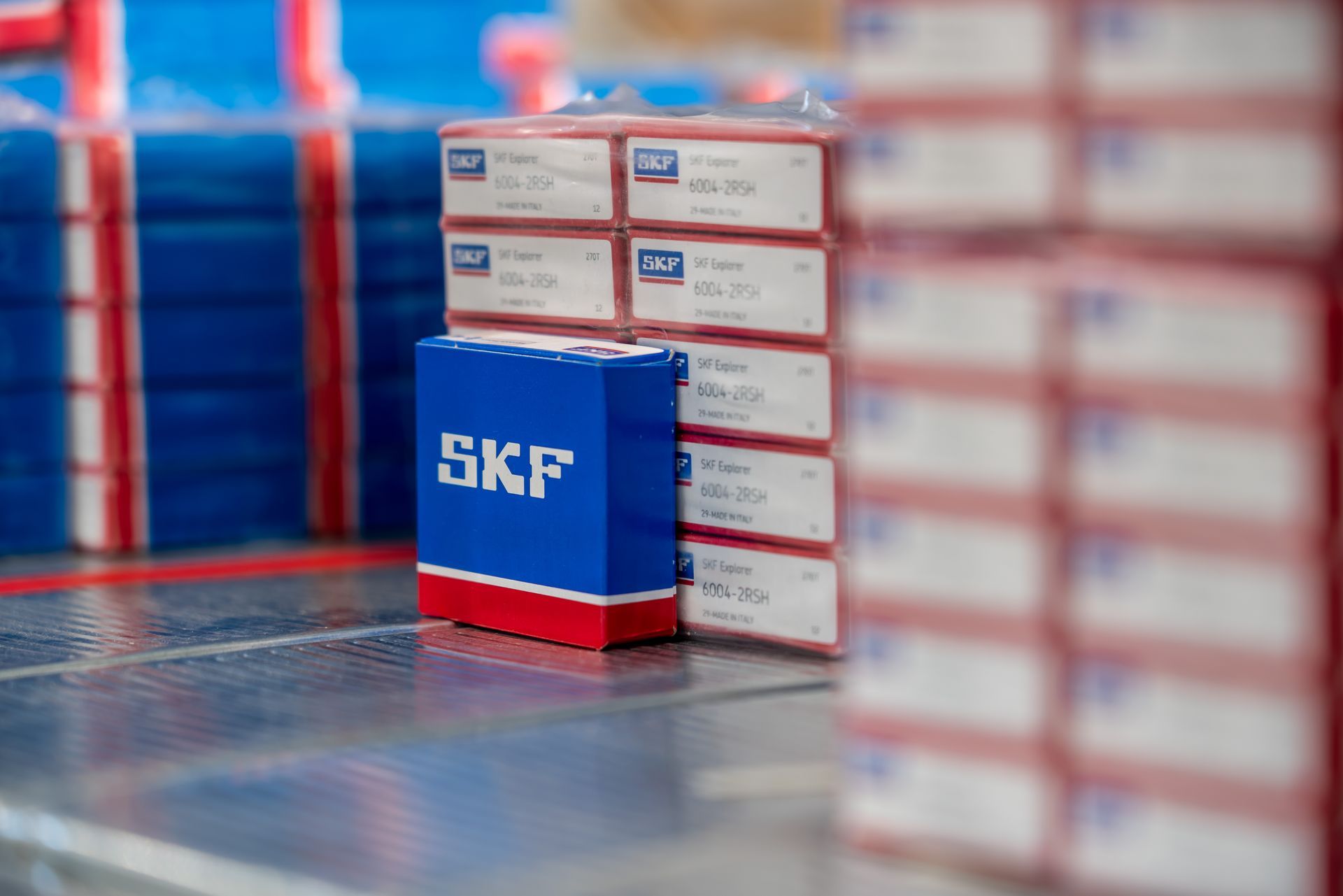 Scatole di cuscinetti SKF impilate, con marchi blu e rossi su una superficie metallica.
