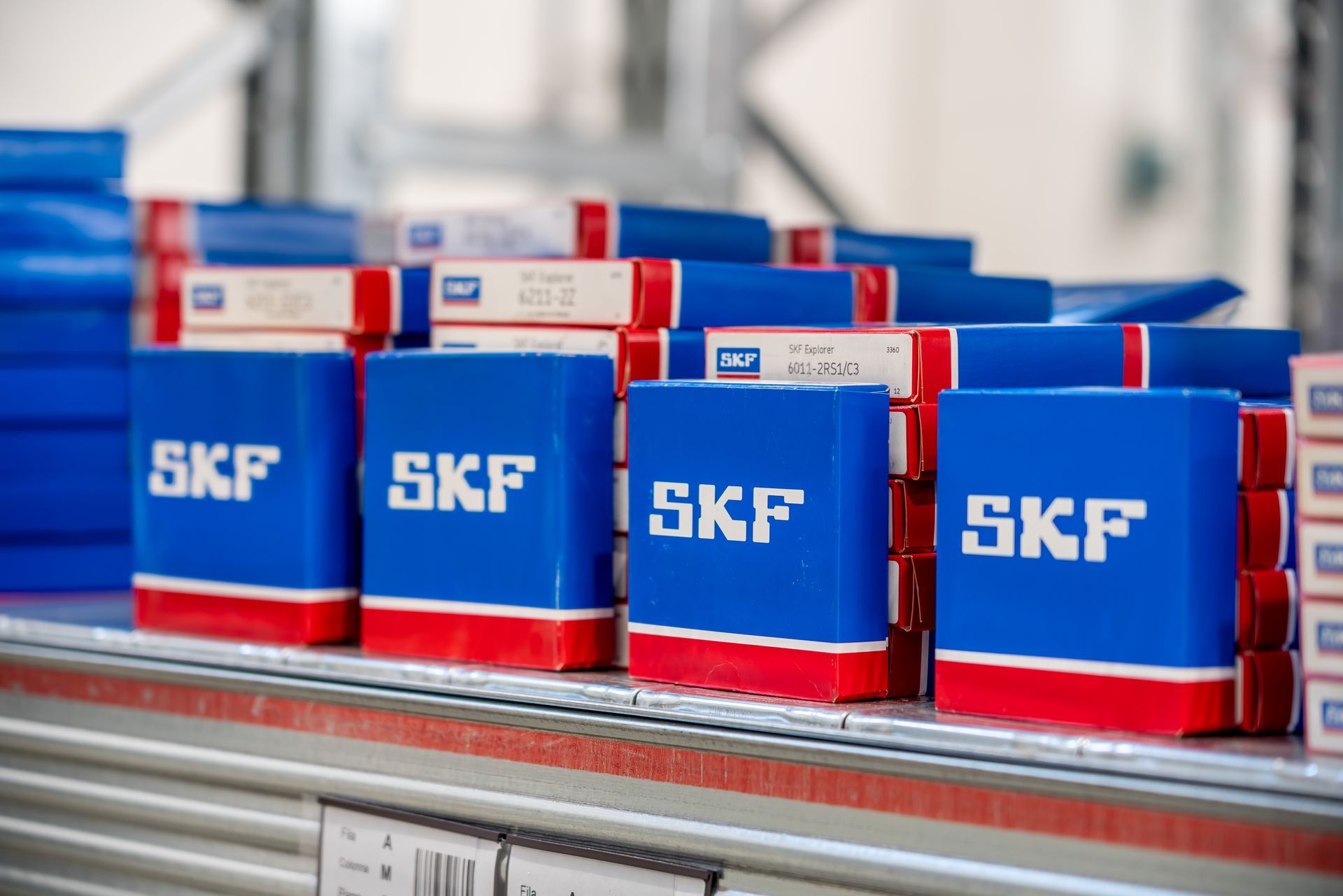 Scatole di cuscinetti SKF blu e rosse impilate su uno scaffale in un magazzino.