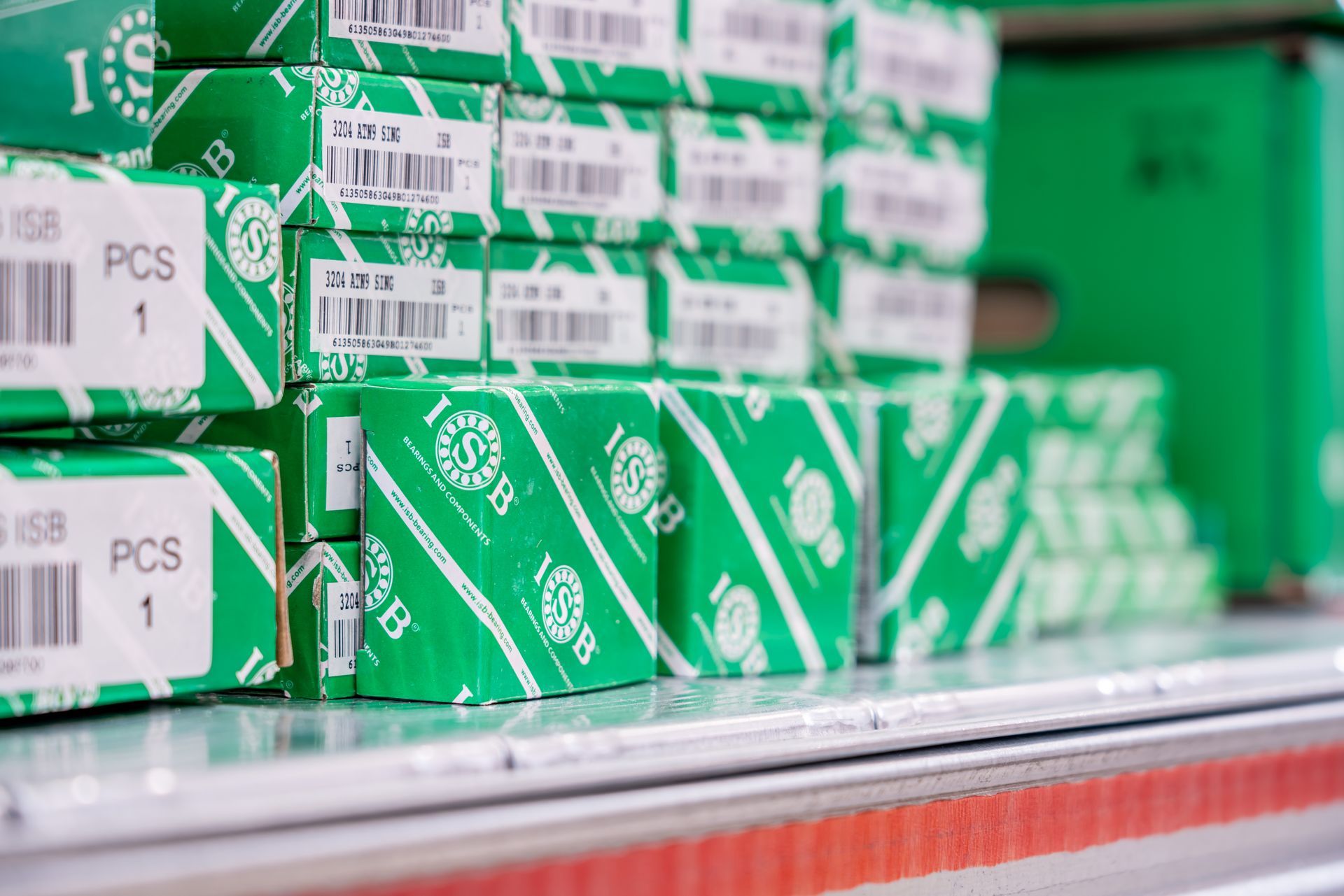 Scatole verdi impilate su uno scaffale, etichettate con testo bianco e codici a barre.