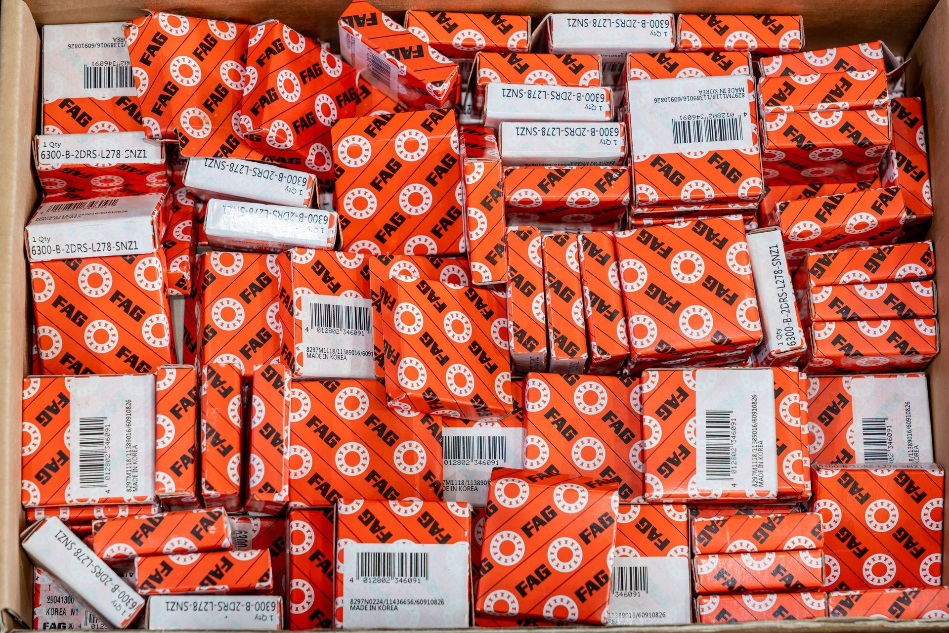 Scatole di pezzi avvolti in carta arancione in una scatola di cartone, ciascuna con un codice a barre.