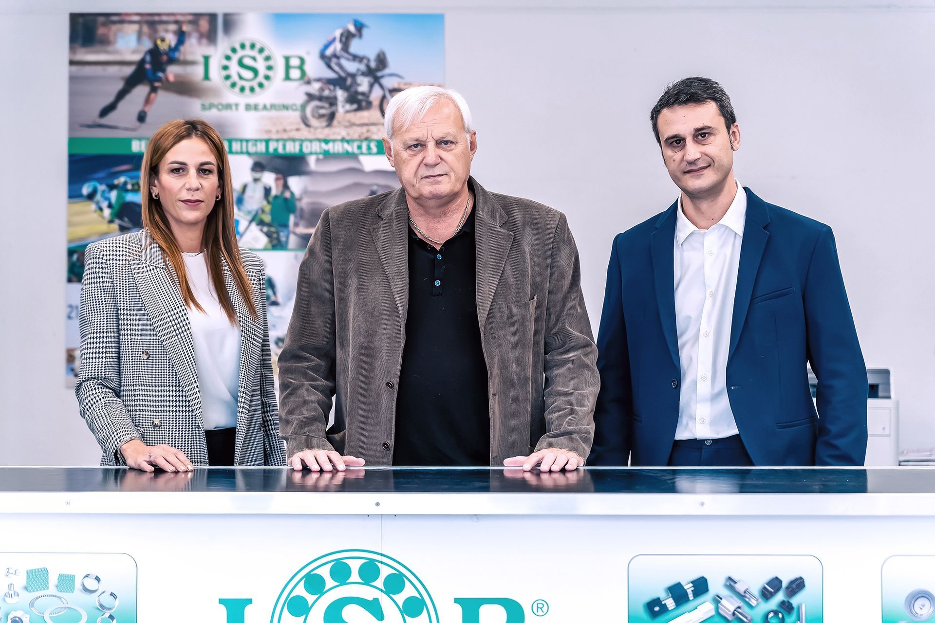 Tre persone in piedi dietro un bancone con il logo 