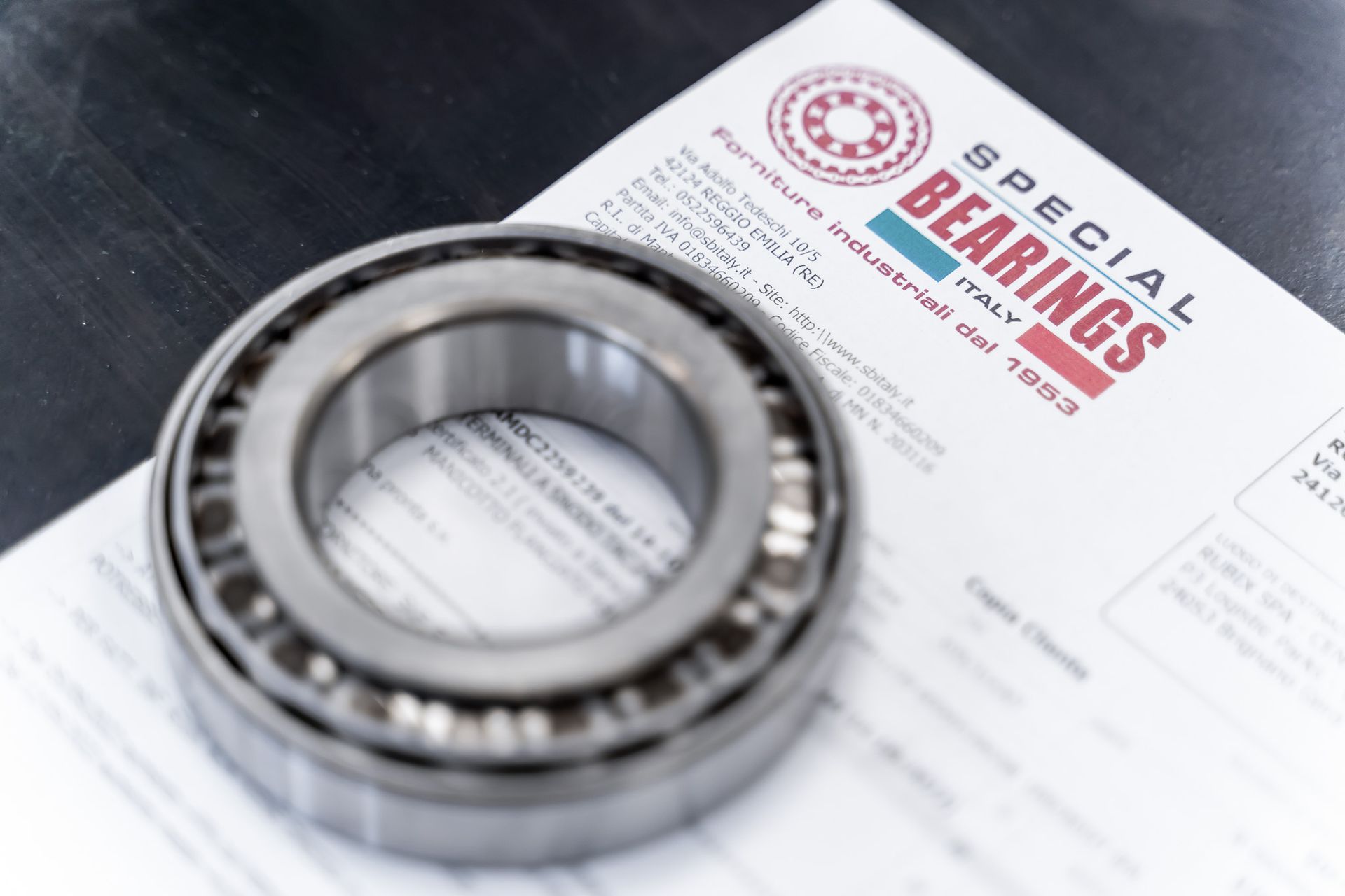 Cuscinetto a rulli conici accanto a un documento con il logo 