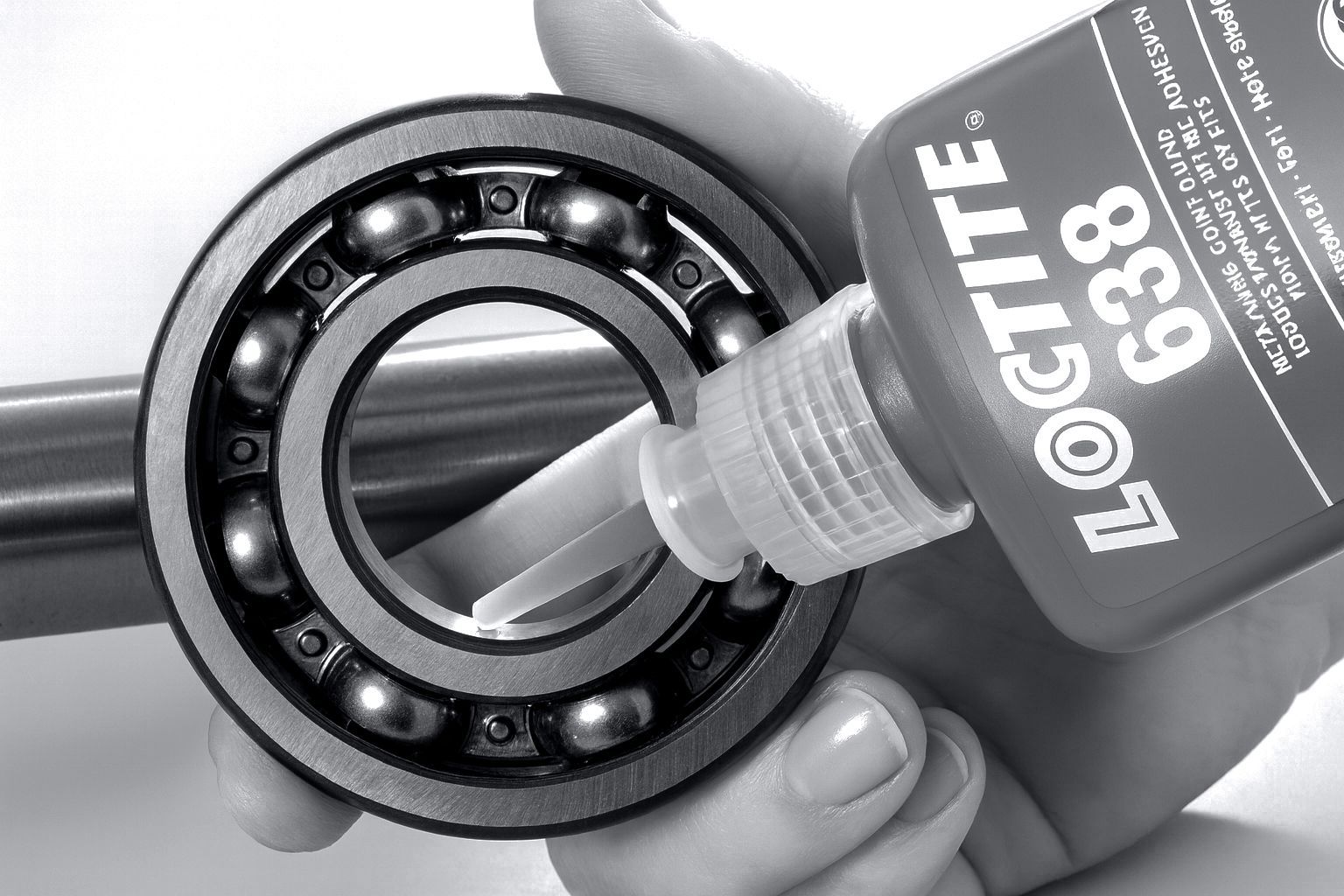 Una mano che applica l'adesivo Loctite 638 su un cuscinetto a sfere, probabilmente per il montaggio.