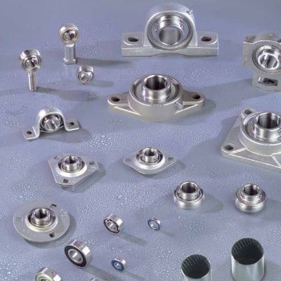 Assortimento di unità cuscinetto e componenti in acciaio inossidabile su una superficie azzurra.