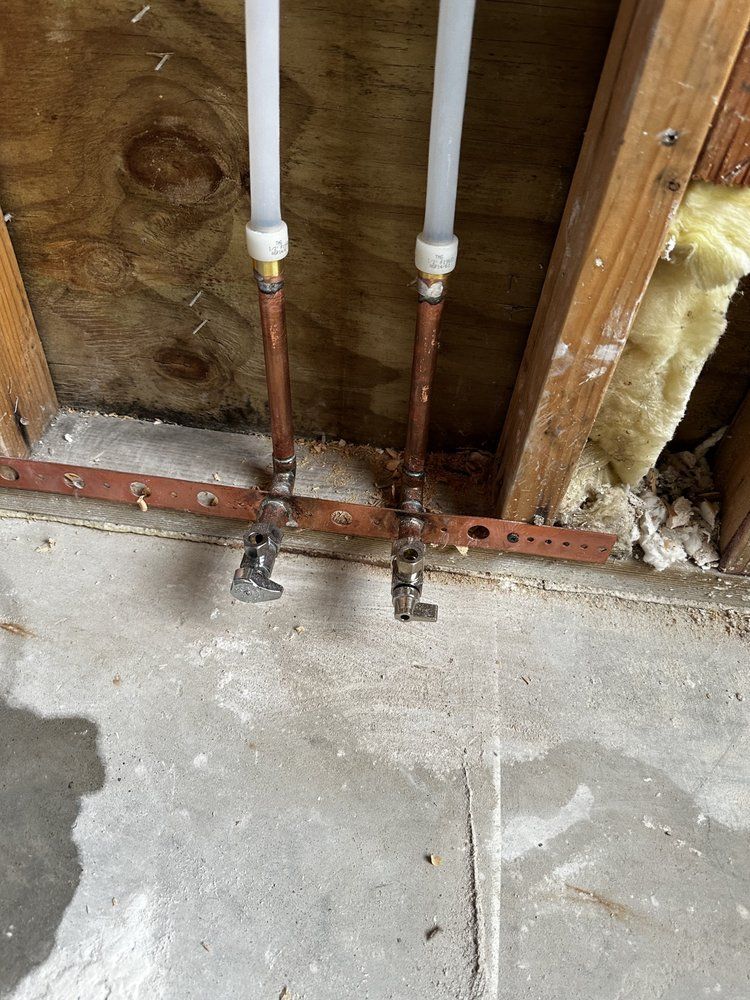 A close up of a copper pipe in a wall.