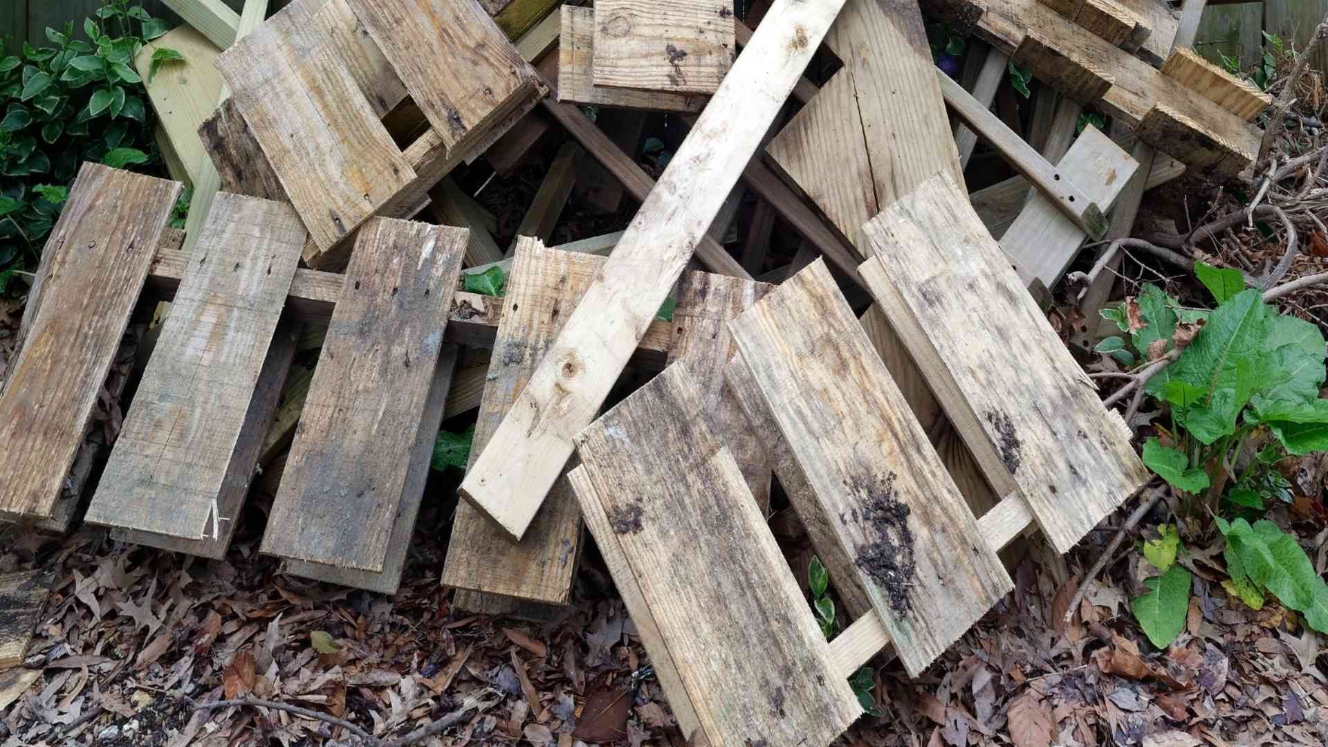 a pile of old grey wood pallets in a yard, yard cleanups