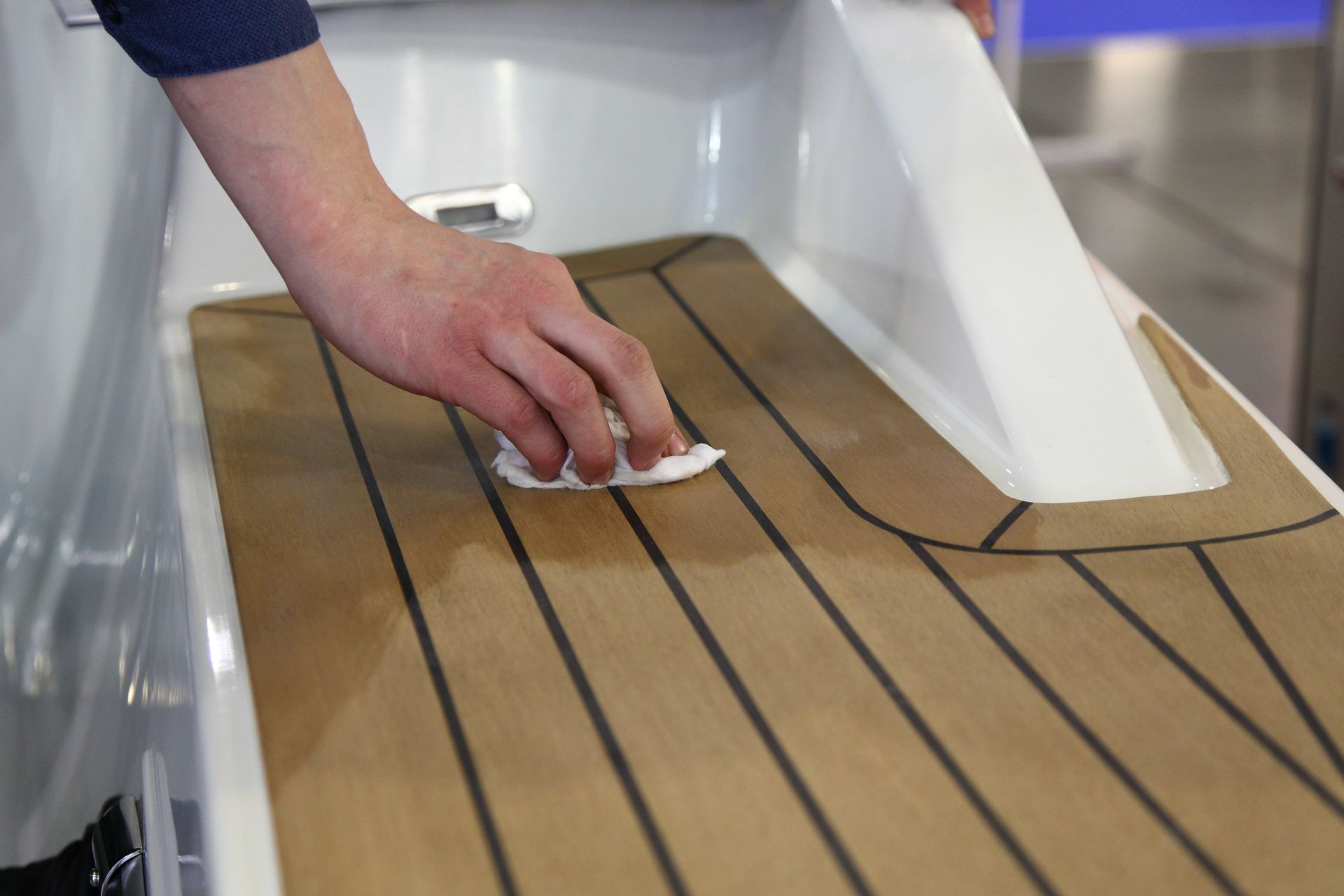 Hand wiping a varnished wooden boat deck with a cloth