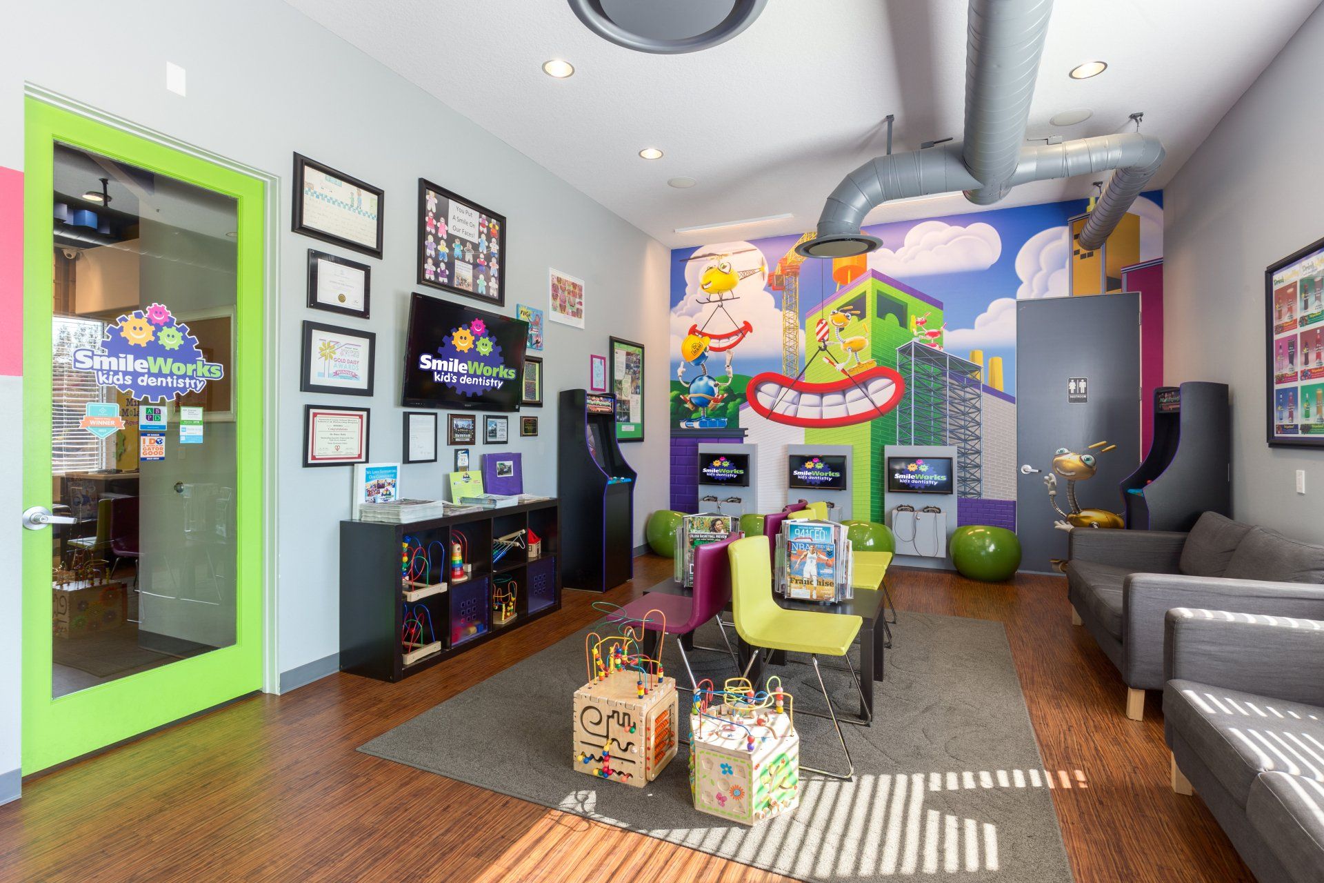 A living room with a couch , chairs , a television and a mural on the wall.