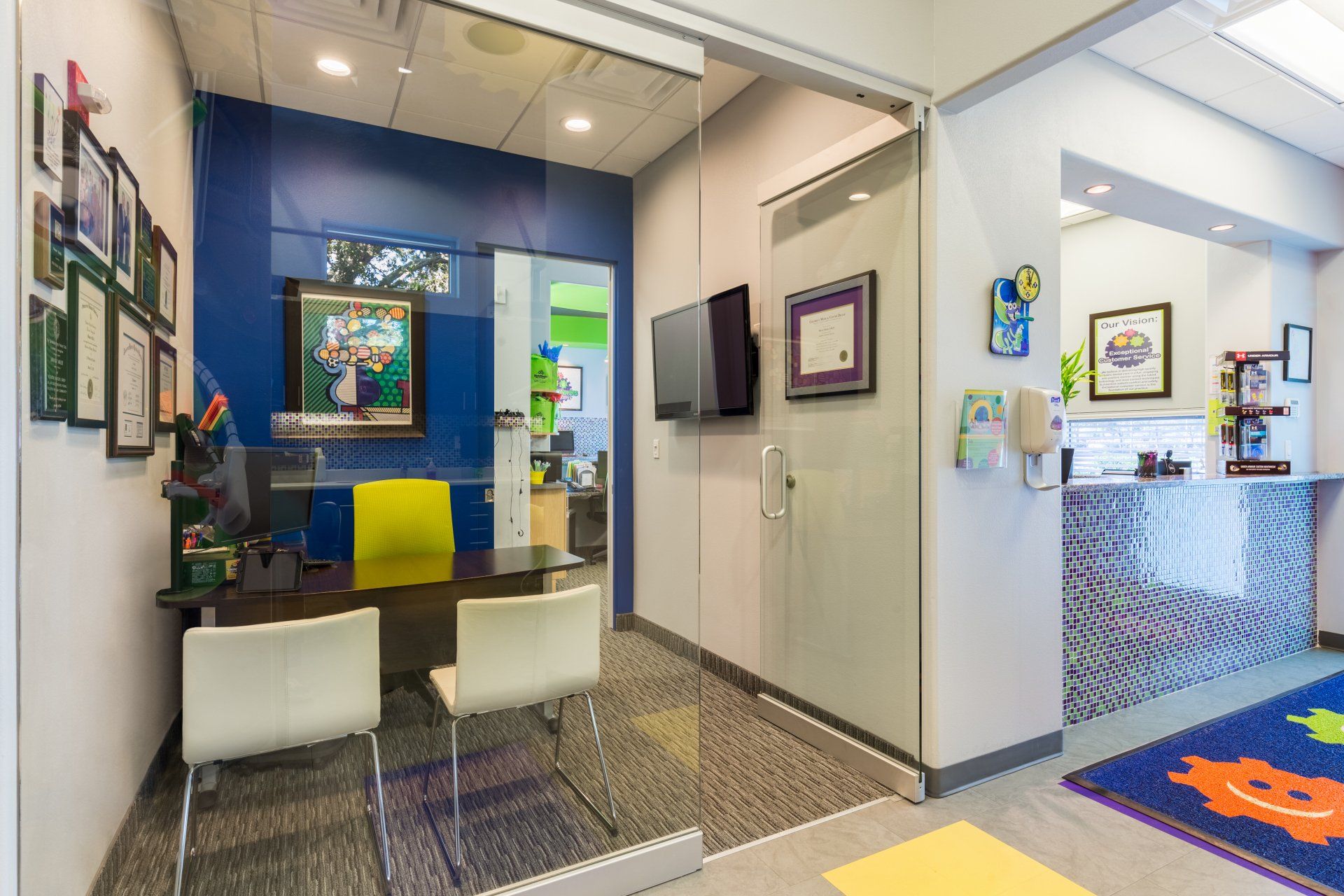 A dental office with a table and chairs and a glass door.