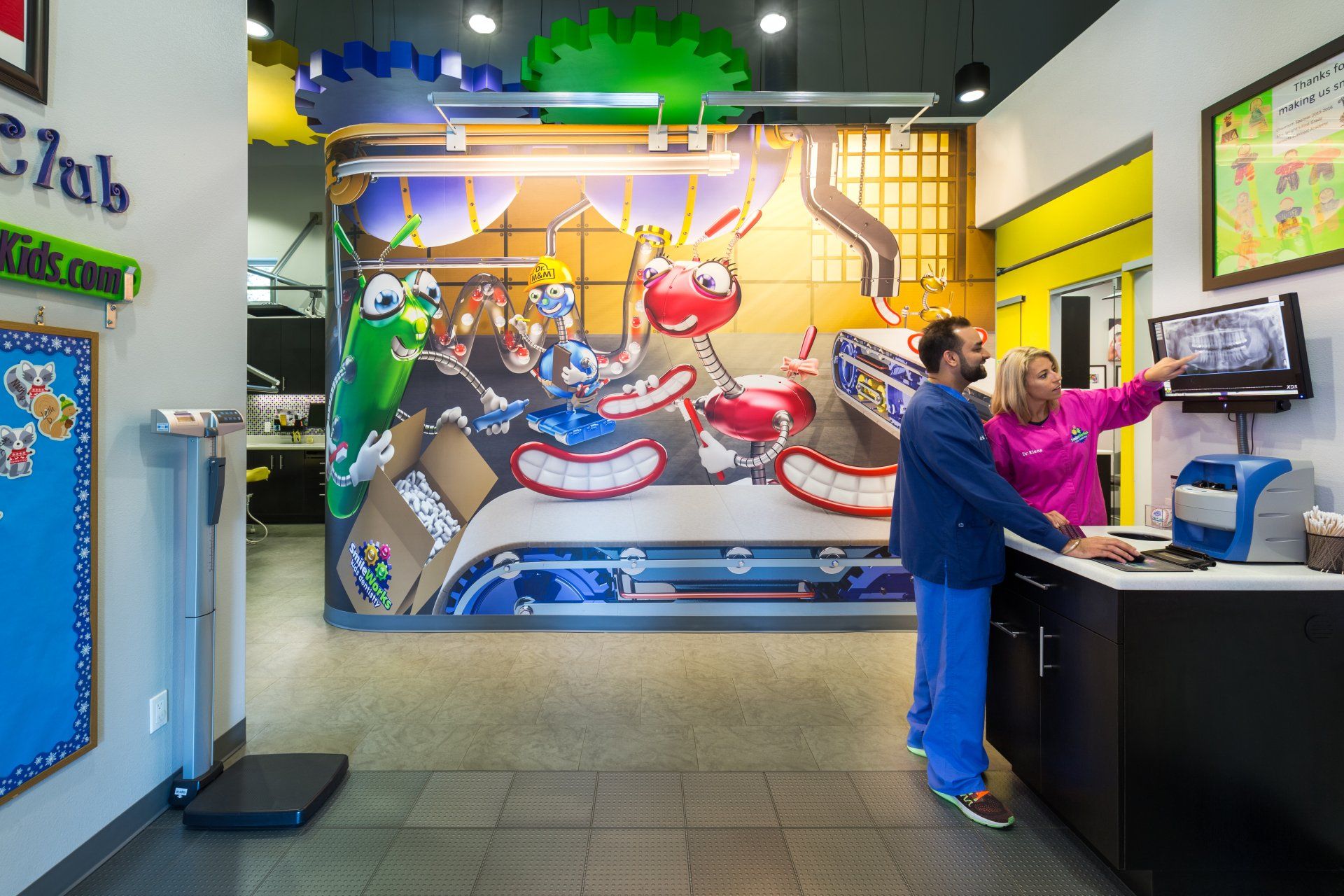 A man and a woman are standing in a room with a mural on the wall.