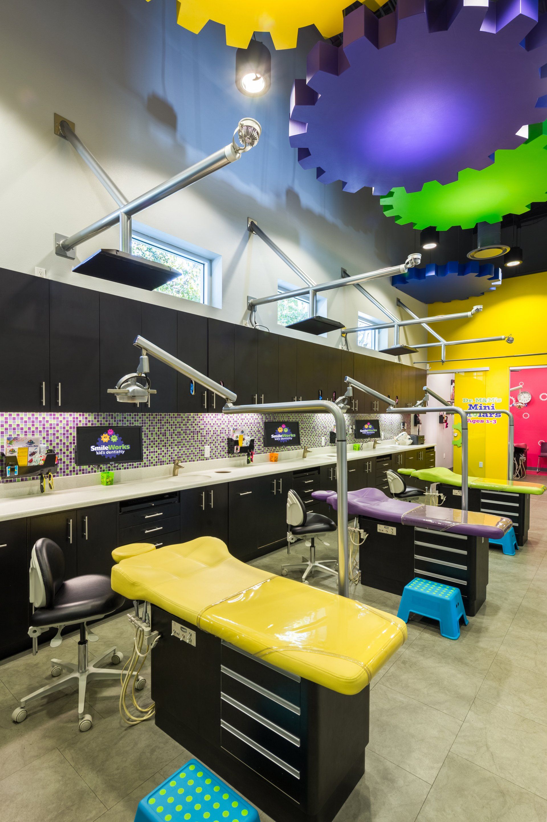 A row of dental chairs in a dental office with a colorful ceiling.