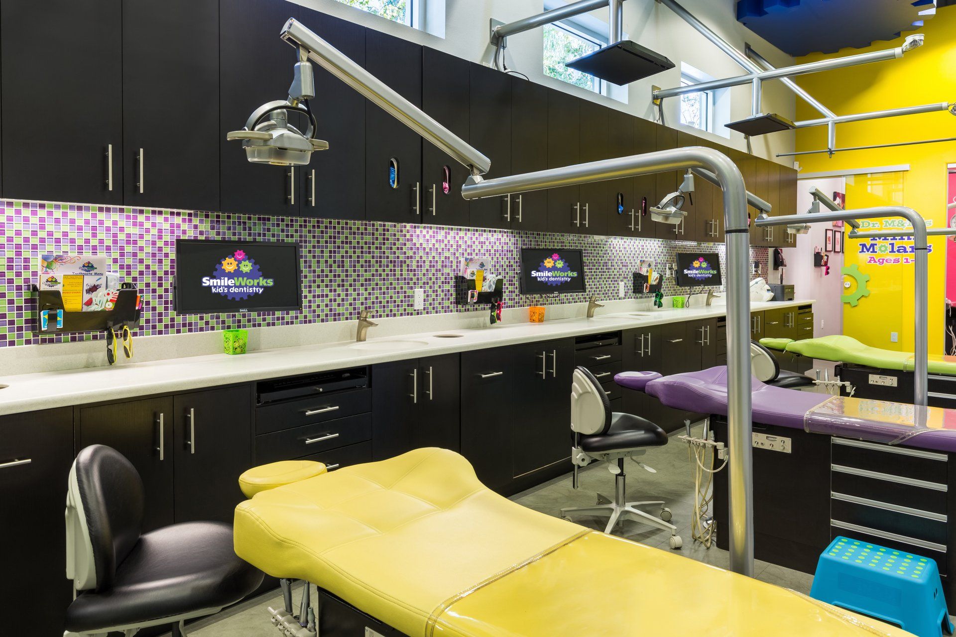 A dental office with a yellow dental chair and purple chairs.