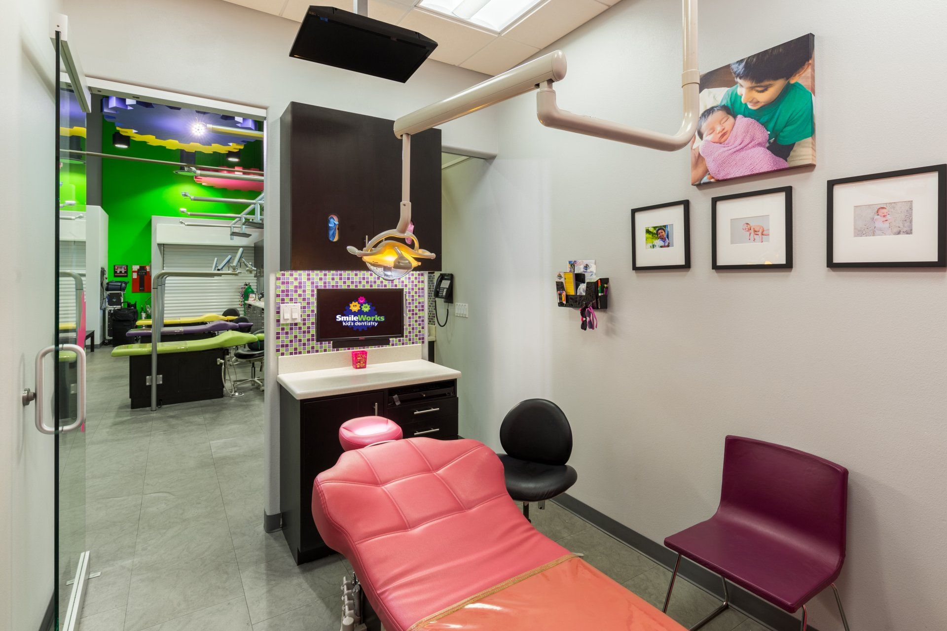 A dental office with a pink dental chair and purple chairs.