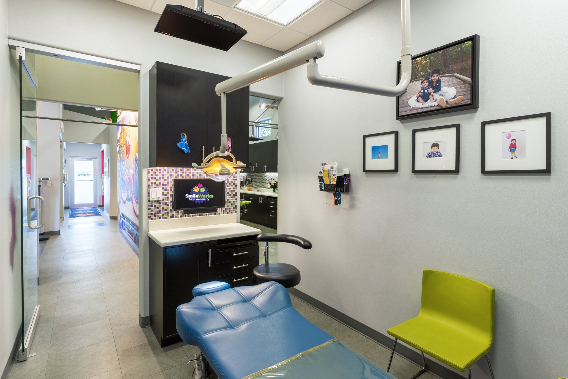 A dental office with a blue dental chair and a green chair.