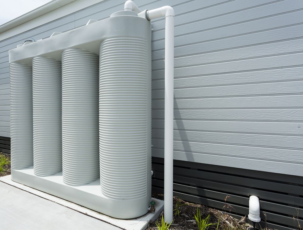 A White Water Tank Is Attached To The Side Of A House — Clear and Clean Water Tank Cleaning Services in Pokolbin, NSW