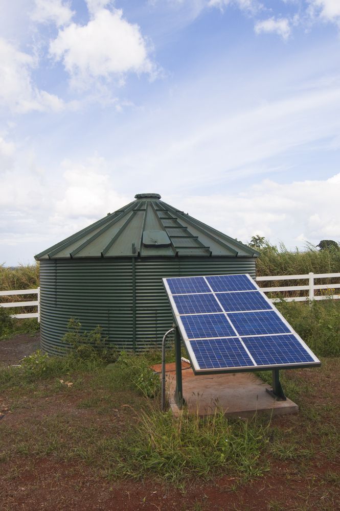 A Solar Panel Is Sitting In Front Of A Water Tank — Clear and Clean Water Tank Cleaning Services in Cessnock, NSW