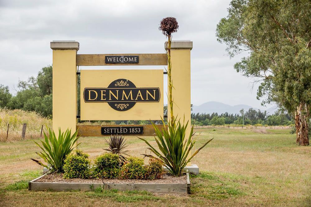 A Yellow Sign That Says Den Man Is In The Middle Of A Field — Clear and Clean Water Tank Cleaning Services in Denman, NSW