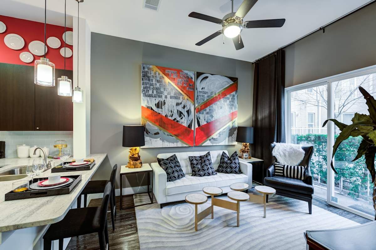 A living room with a couch , chairs , tables and a ceiling fan.