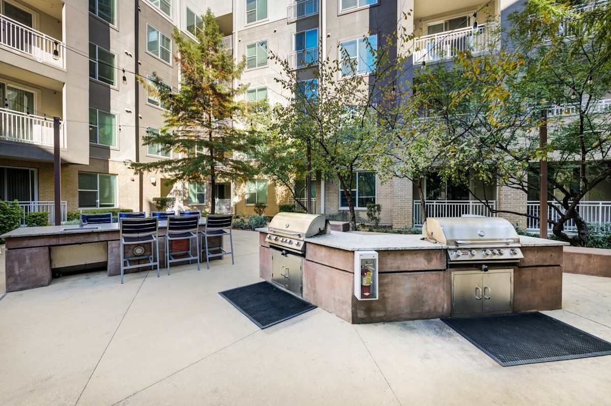There are two grills in the middle of a courtyard in front of a building.