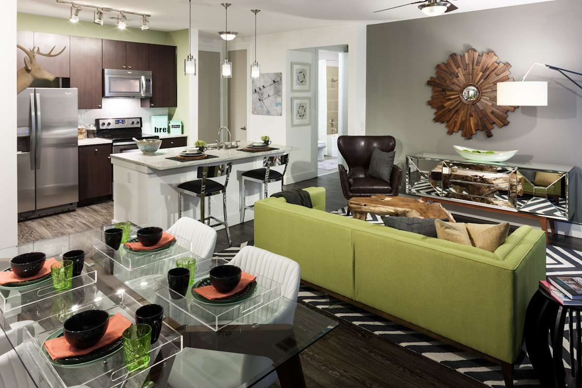 A living room with a green couch and a dining table
