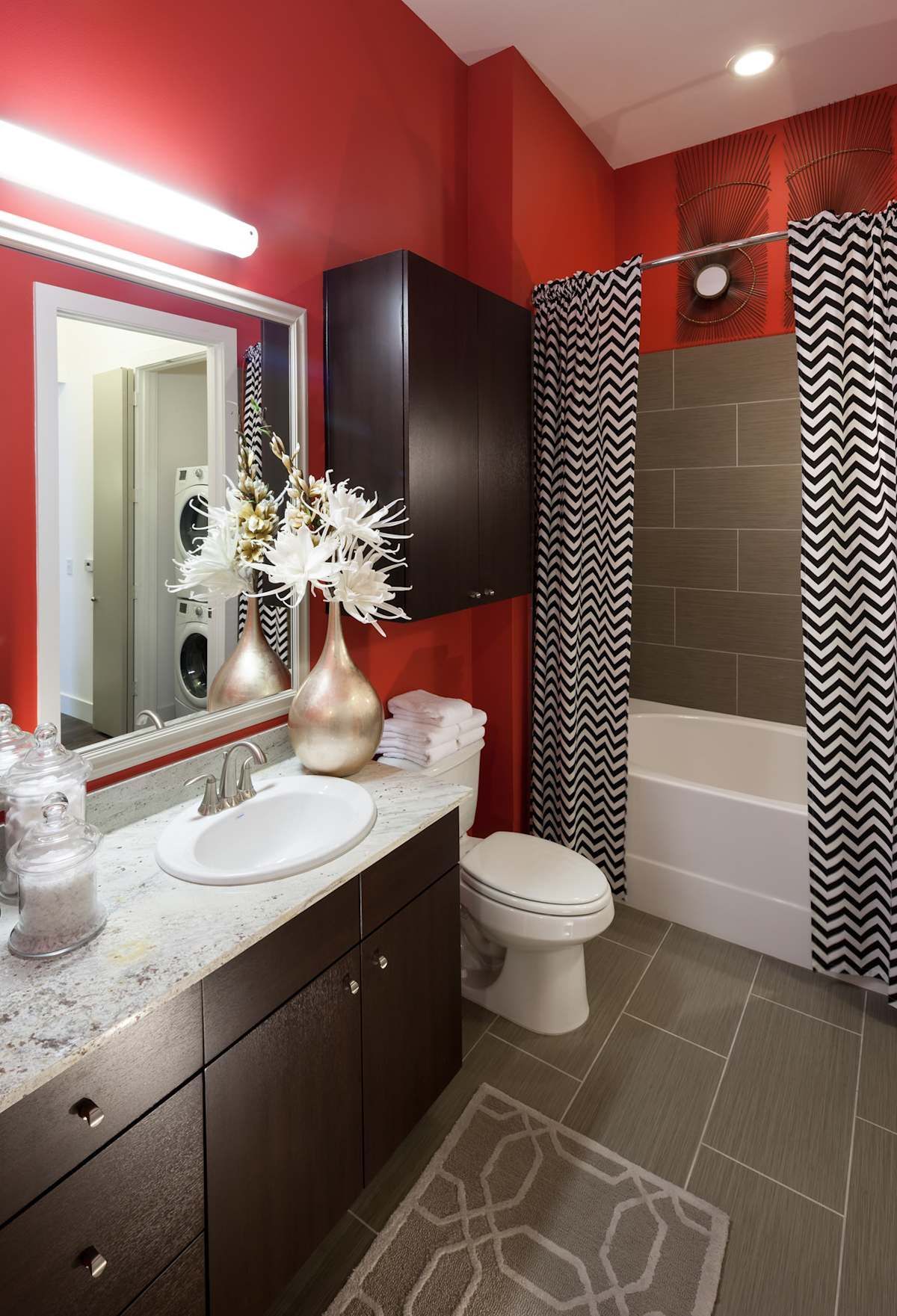 A bathroom with red walls , a sink , toilet and bathtub