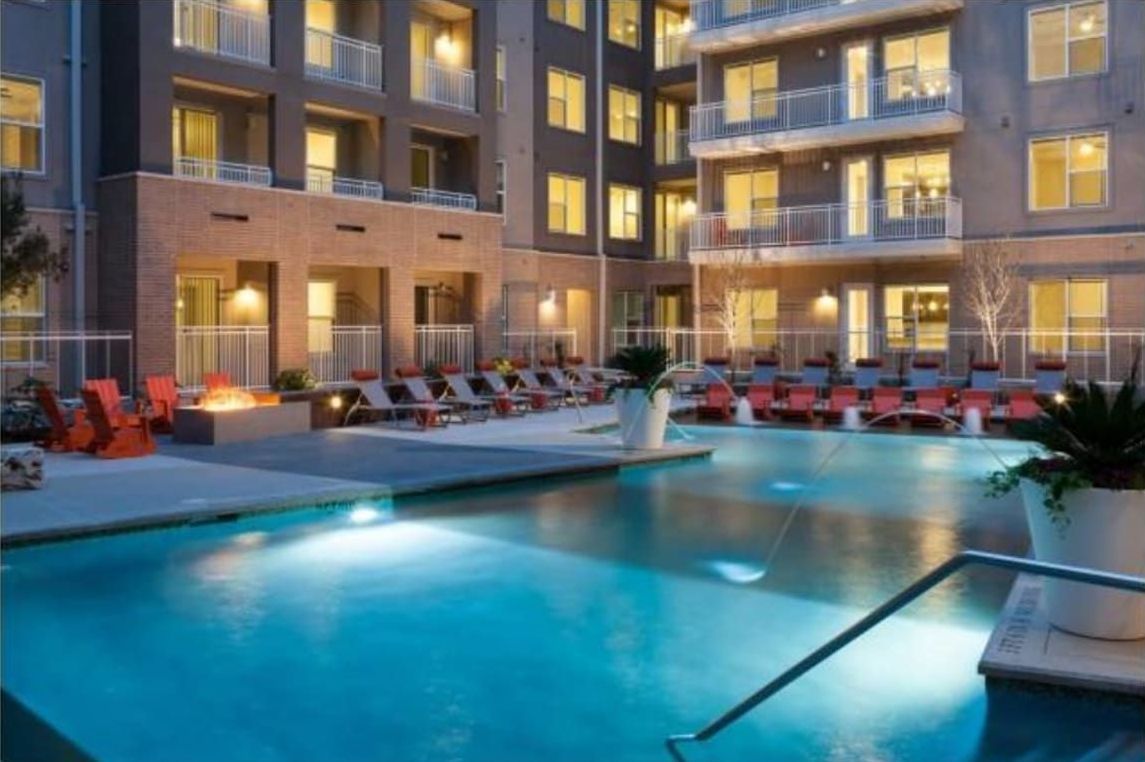 Lobby with green and neutral decor; seating areas, sculptural lighting, and textured wall.