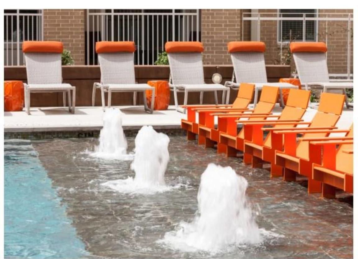 A swimming pool with chairs and fountains surrounding it