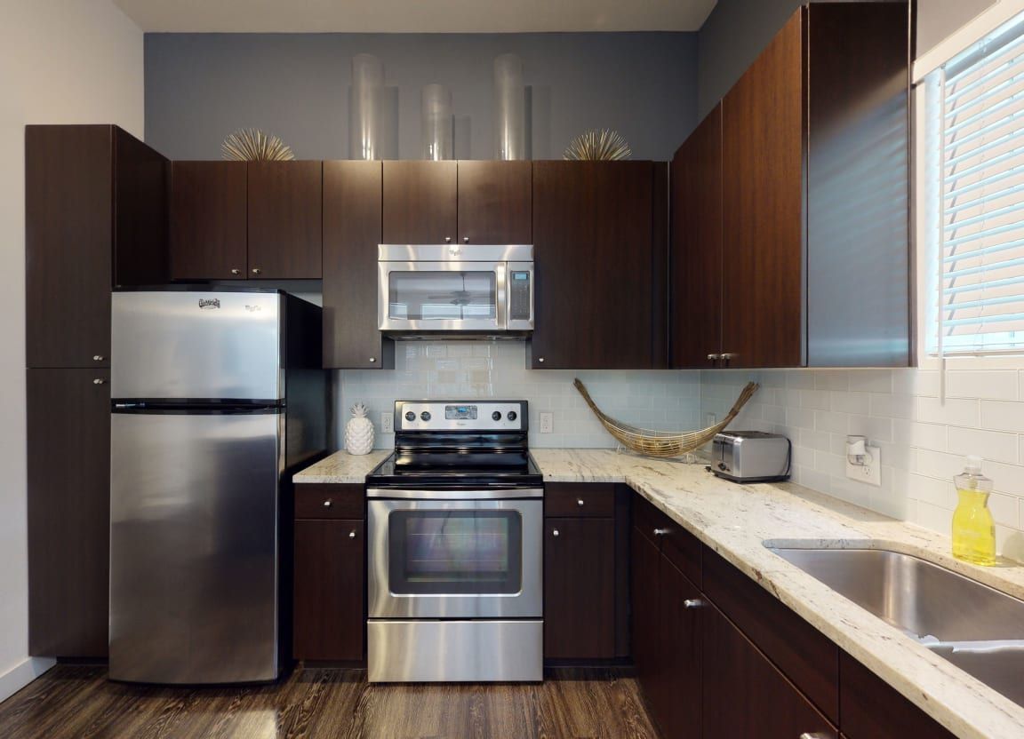 A kitchen with stainless steel appliances and brown cabinets