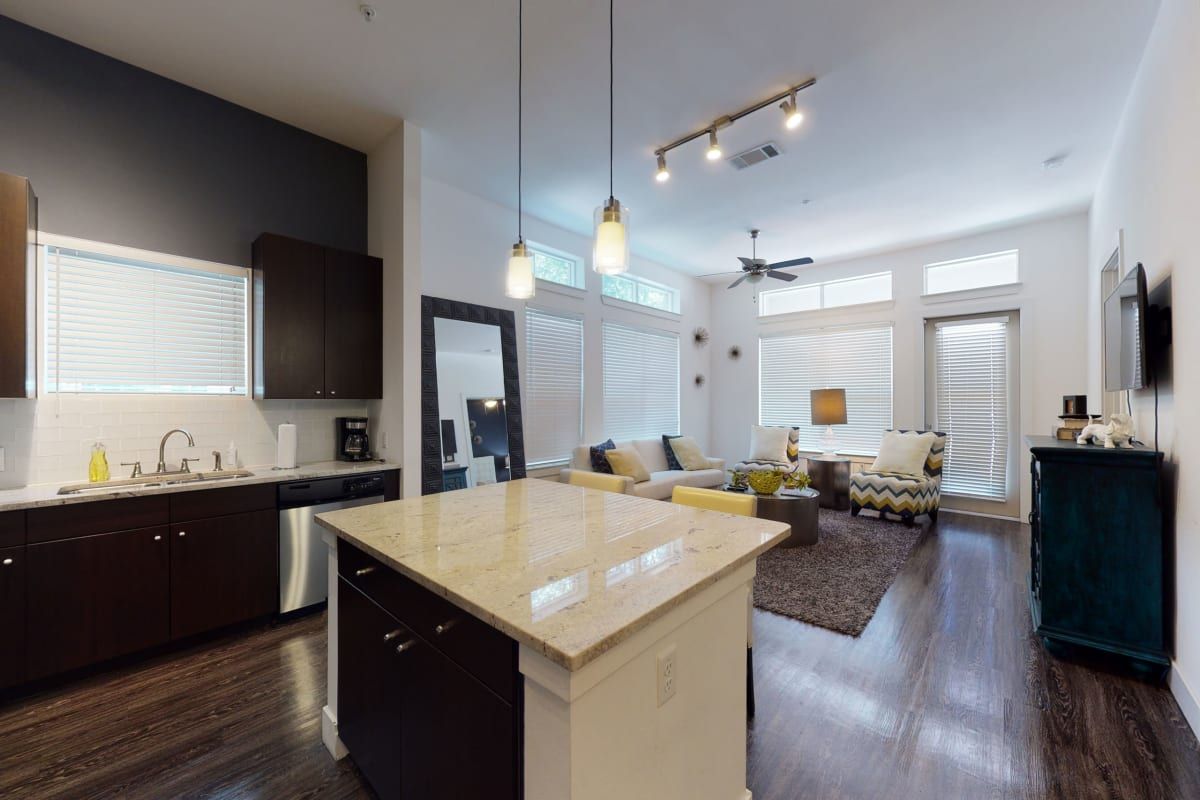 A kitchen and living room in a house with a large island in the middle.